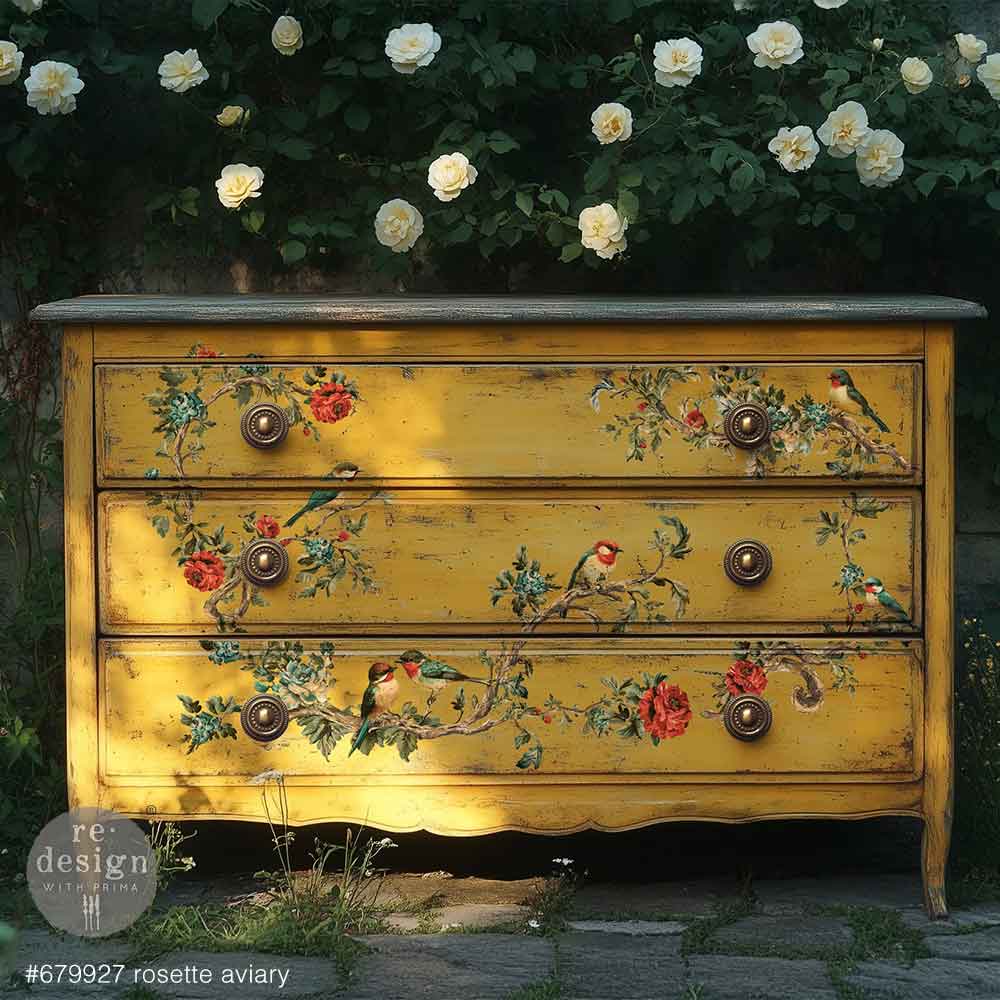 Yellow dresser with floral and bird designs outdoors with white flowers in the background