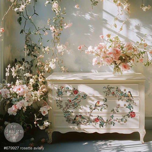 Decorative chest of drawers with floral and bird patterns, surrounded by flowers and greenery.