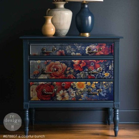 Floral-patterned dresser with decorative vases and lamp against a dark wall.