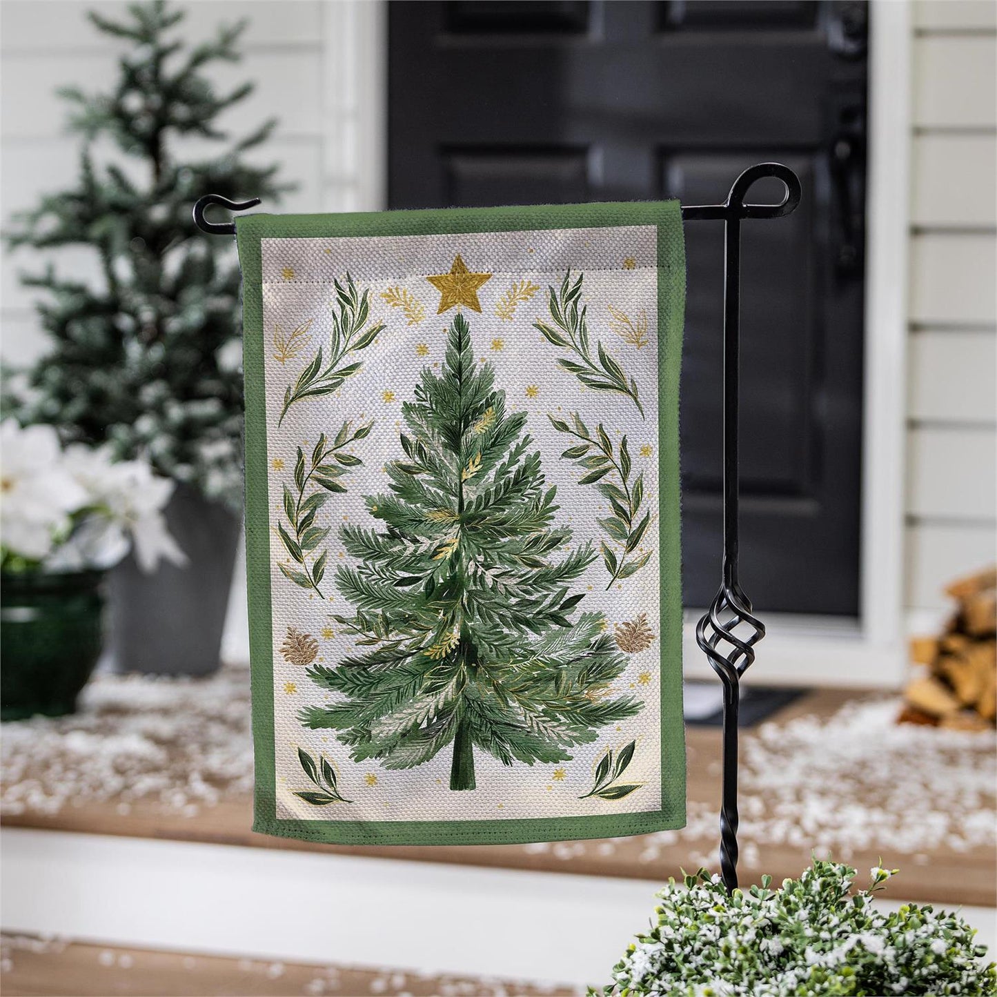Decorative garden flag with Christmas tree design on a stand outdoors.