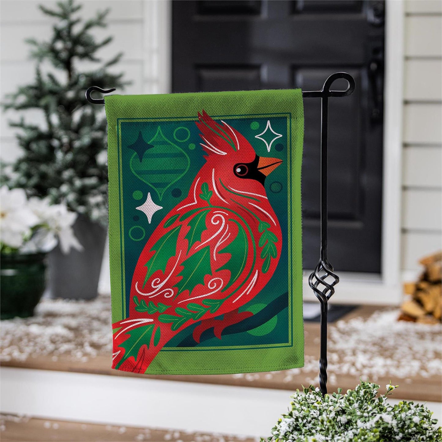 Decorative garden flag with a red cardinal design on a stand outdoors.