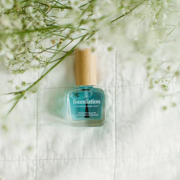 Reminder Foundation Base Coat on a white fabric background with flowers.