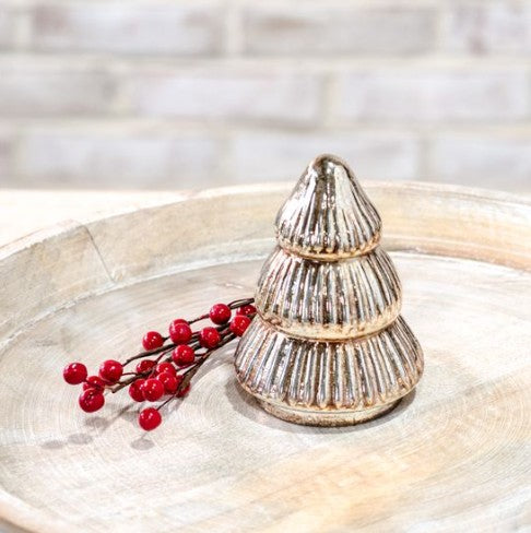 Decorative silver Christmas tree ornament on a marble surface with red berries.