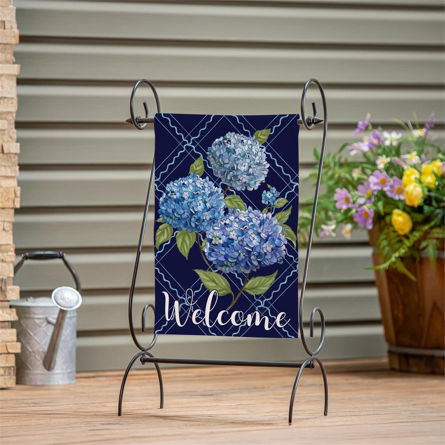 Hydrangea Haven garden flag with blue hydrangea design on a garden flag stand, hanging outdoors.