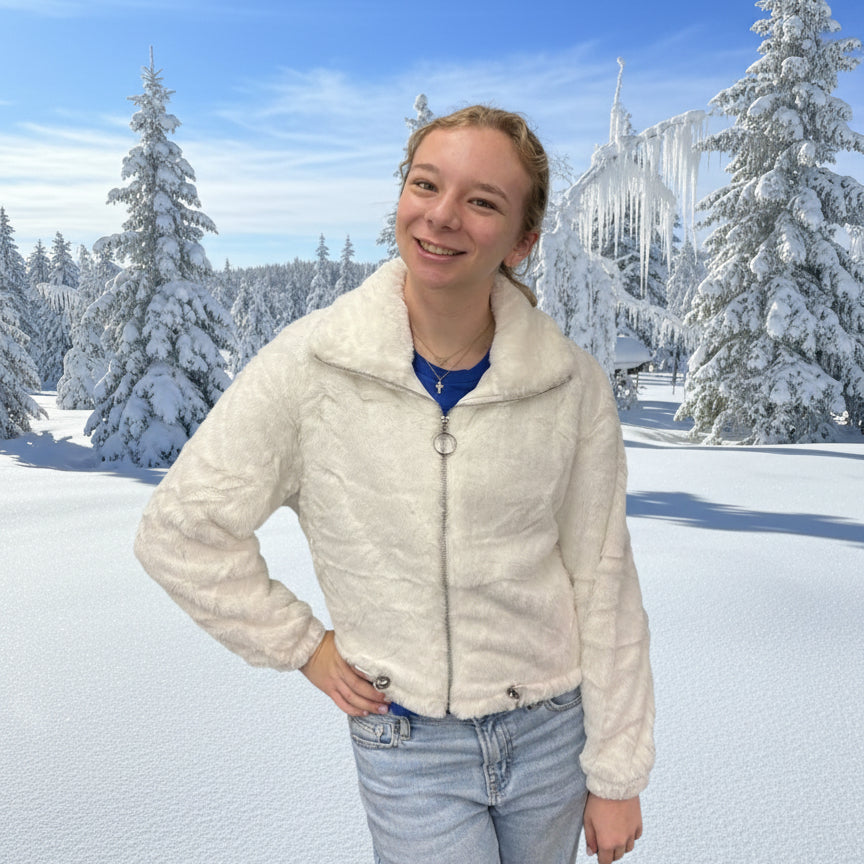 Person wearing a white jacket in a snowy landscape.