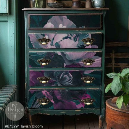 Floral-patterned chest of drawers with gold handles against a dark green wall.