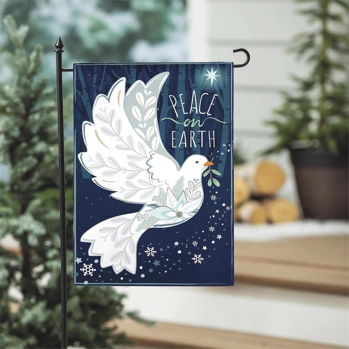Decorative flag with a dove and 'Peace on Earth' text in a garden setting.