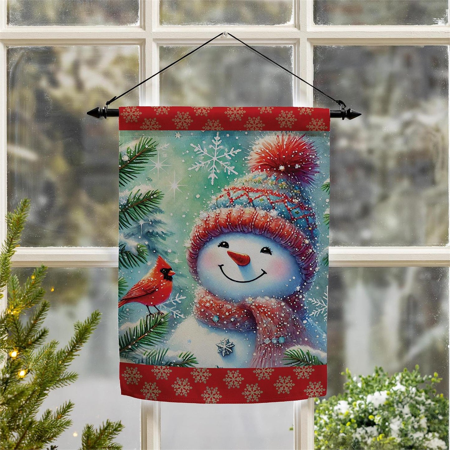 Decorative Christmas flag with a snowman, cardinal, and snowflakes in front of a window.