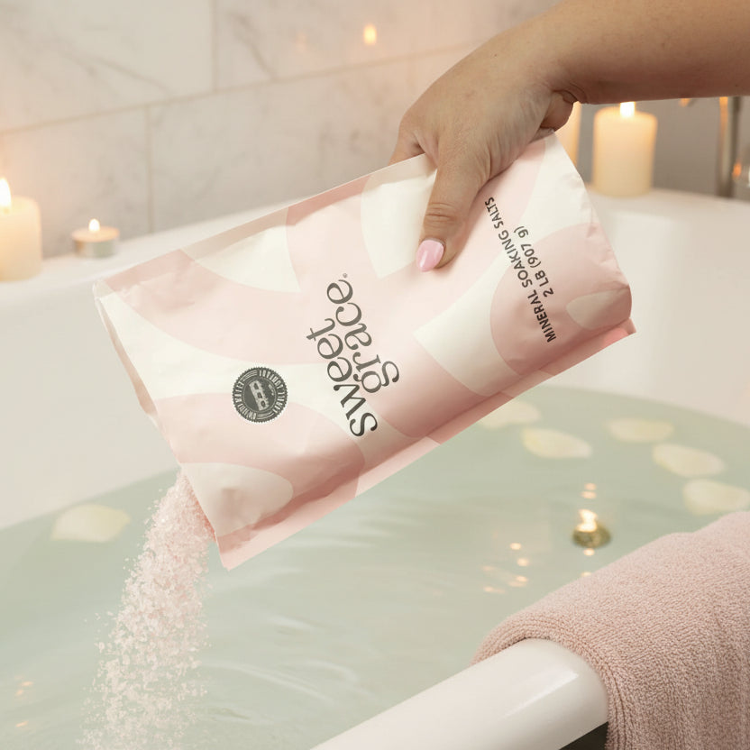 A hand pouring a bag of Sweet Grace Soaking Salts into a bath