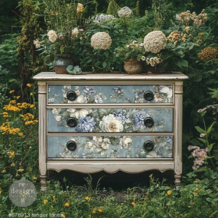Decorative chest of drawers with floral patterns in a natural setting with flowers and plants.