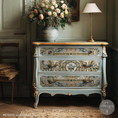 A dresser shown with the Serenade in Blue decoupage paper with flowers and a lamp on top.
