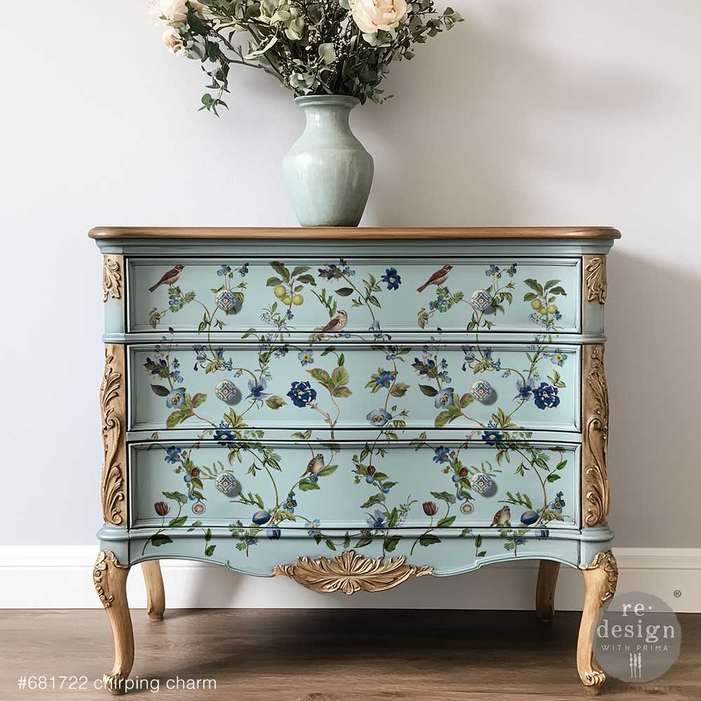 Blue dresser decorated with the Chirping Charm decor transfers on a grey wall with a vase and flowers on top.