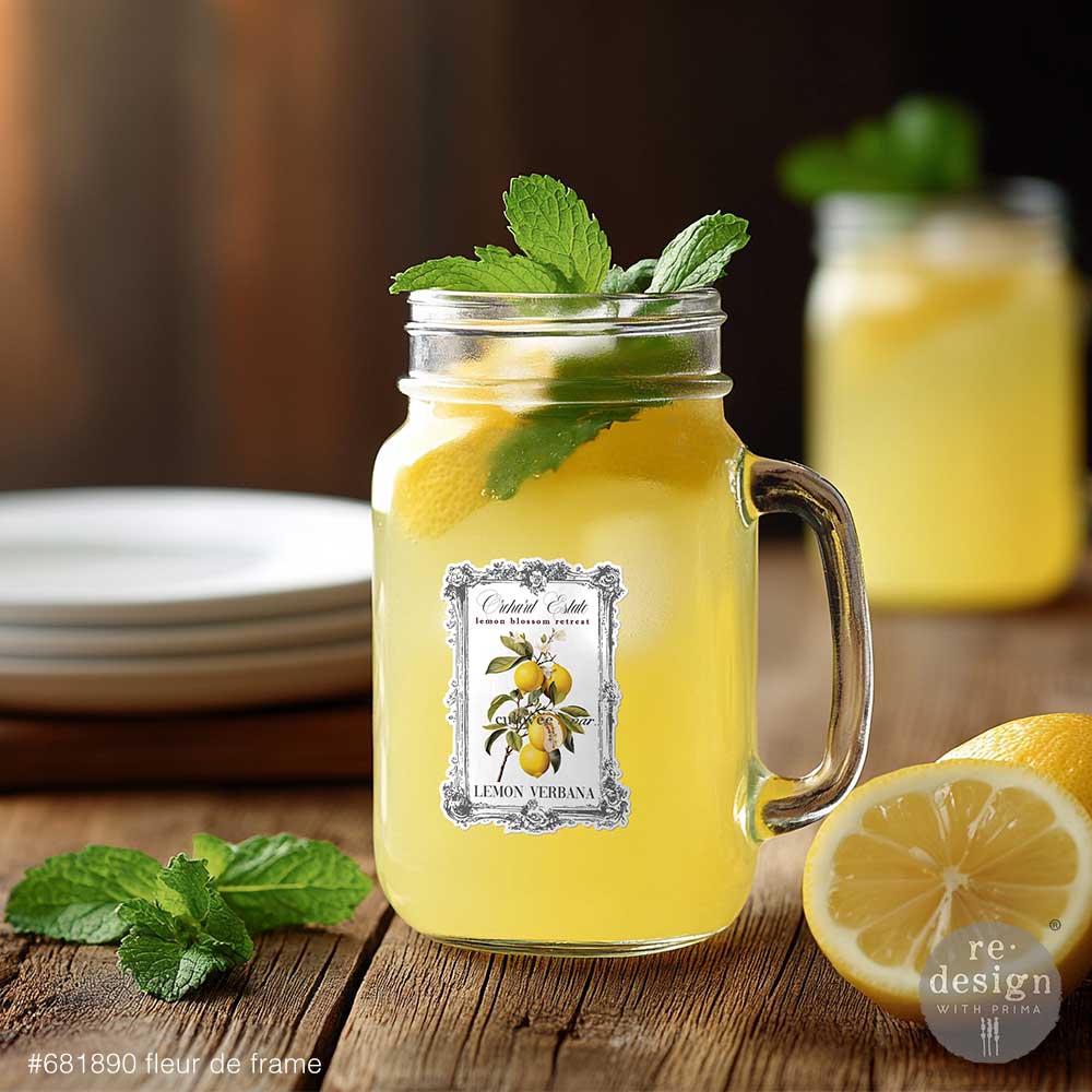 Mason jar with lemonade and mint leaves decorated with Fleur De Frame Luxe Transfers on a wooden surface, with another jar and lemons in the background.