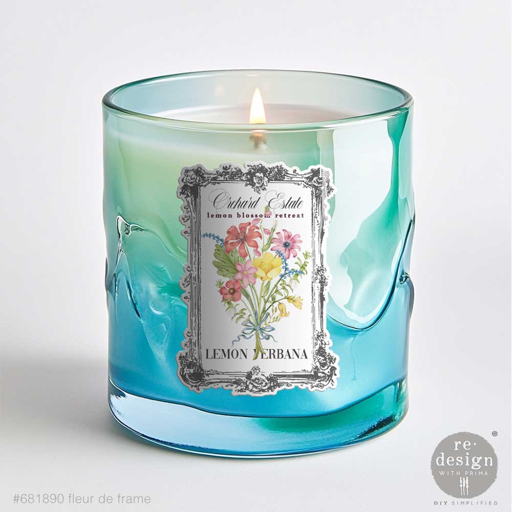 Candle in a blue glass container with Fleur De Frame Luxe Transfers on a white background
