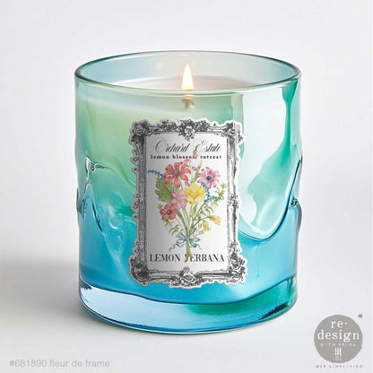 Candle in a blue glass container with Fleur De Frame Luxe Transfers on a white background
