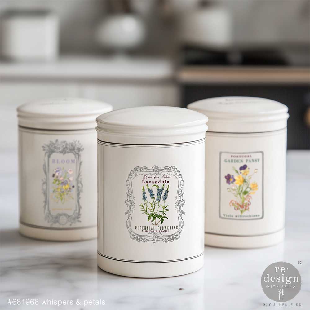 Three decorative storage jars with Whispers & Petals H2O transfers on a marble surface.