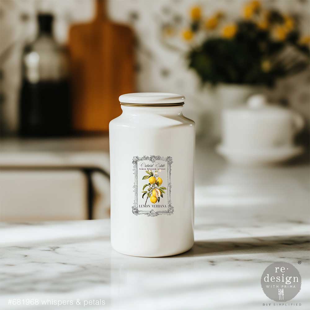 White ceramic jar with Whispers & Petals H2O transfers on a marble surface.