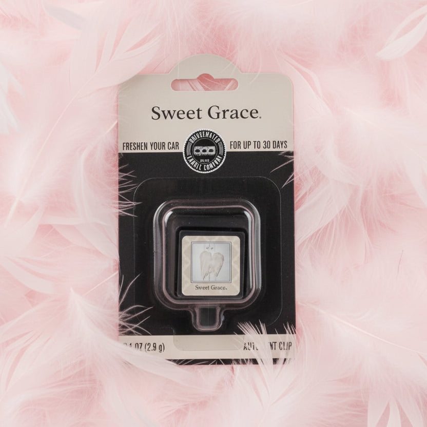 Sweet Grace Auto Vent Clip in packaging shown on a bed of pink feathers