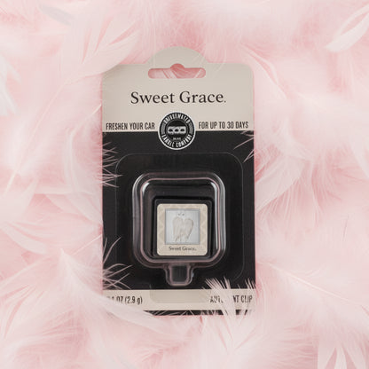 Sweet Grace Auto Vent Clip in packaging shown on a bed of pink feathers