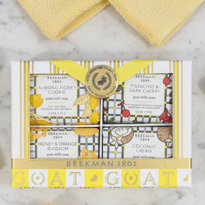 Beekman 1802 Goat Milk Bar Soap set in a gift box on a marble surface. Scents include Almond Honey Cookie, Coconut Cream, Honey & Orange Blossom, and Pistachio & Dark Cherry.