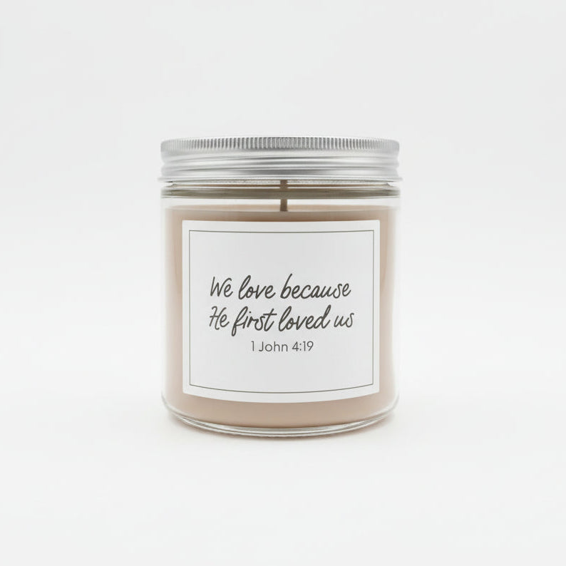 Sweet Grace jar candle with white label and "We love because He first loved us" in black on a white background.