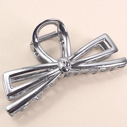 Hematite bow-shaped hair clip on a beige background