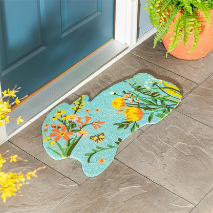 Bunny shaped coir mat with floral design on a stone floor next to a blue door.