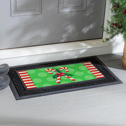 Decorative doormat with candy canes on a green background in front of a door.