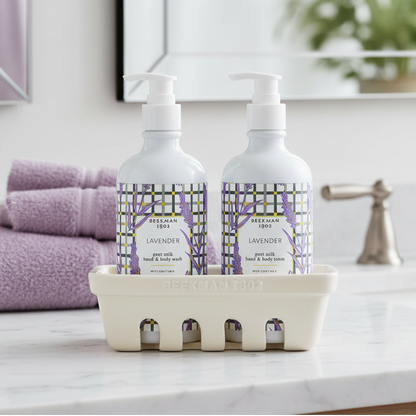 Two bottles of Beekman 1802 lavender goat milk hand and body wash and lotion with a caddy