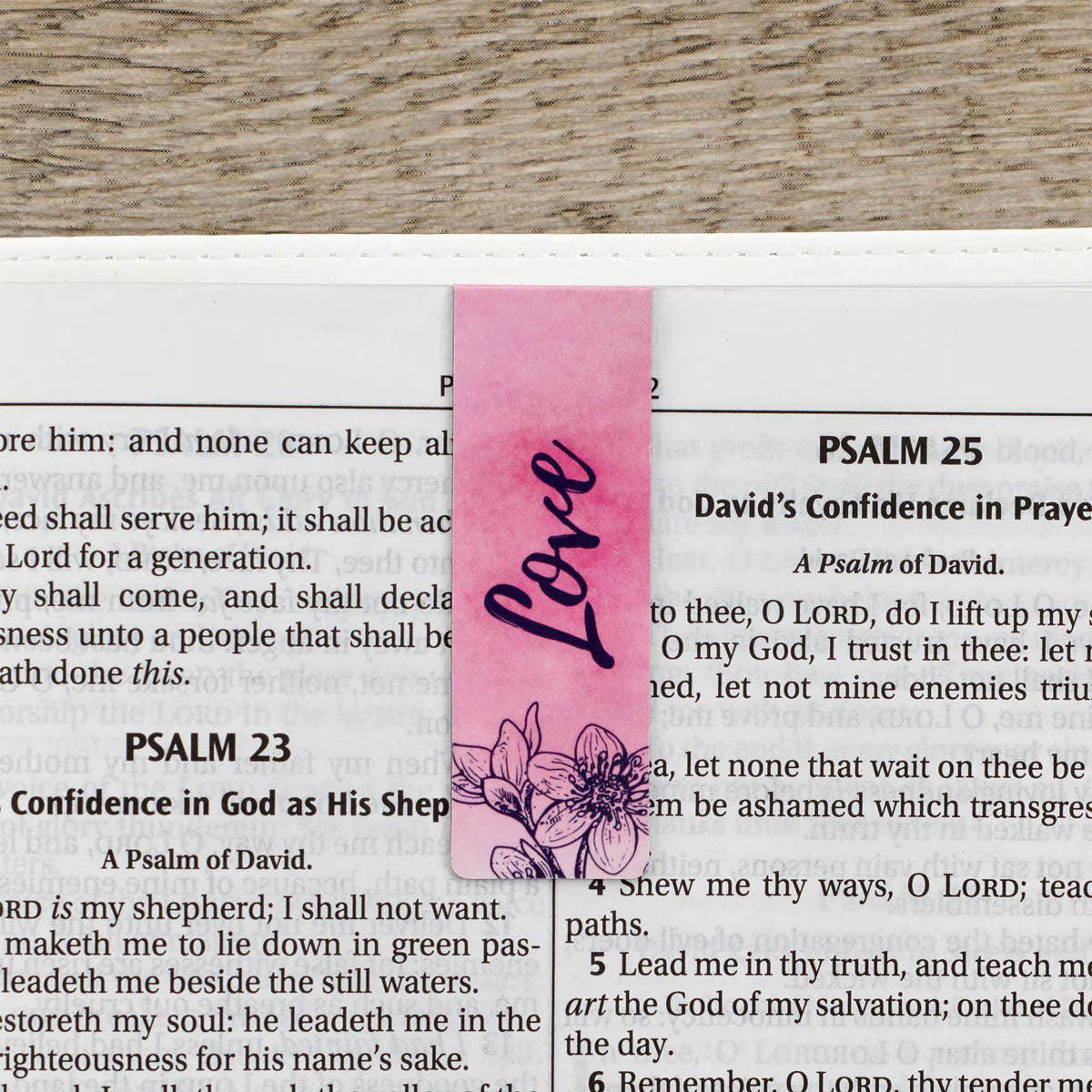Pink bookmark with 'Love' and a flower design on a Bible page.