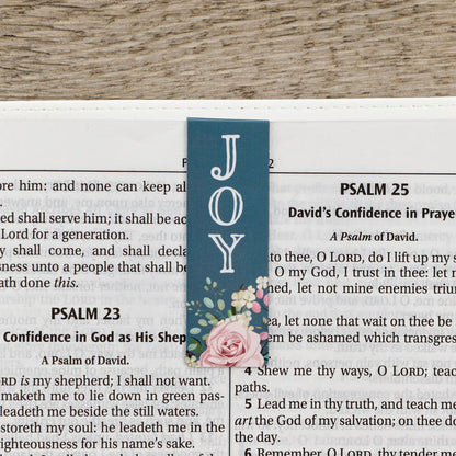 Blue bookmark with floral design and 'JOY' text on a Bible page