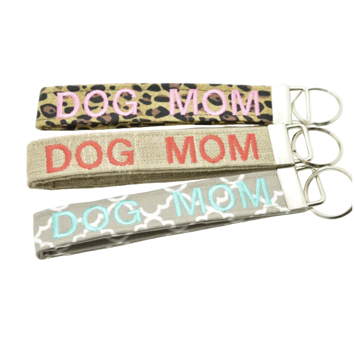 Three keychains embroidered with DOG MOM on leopard print, burlap style, and quatrefoil fabric on a white background.