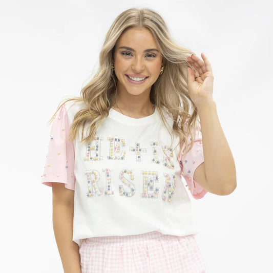 Woman wearing a white t-shirt with colorful He Is Risen text and a pink checkered skirt on a white background