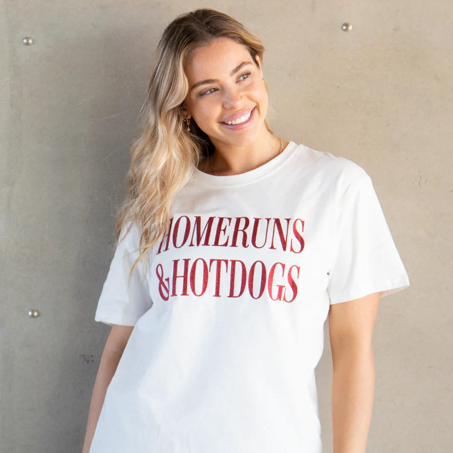 Woman wearing a white t-shirt with 'HOMERUNS & HOTDOGS' text against a plain background