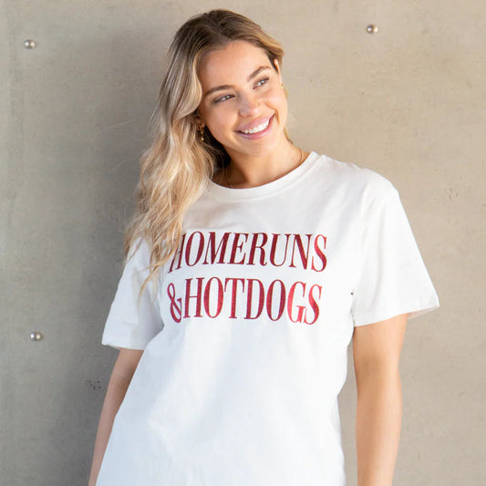 Woman wearing a white t-shirt with 'HOMERUNS & HOTDOGS' text against a plain background