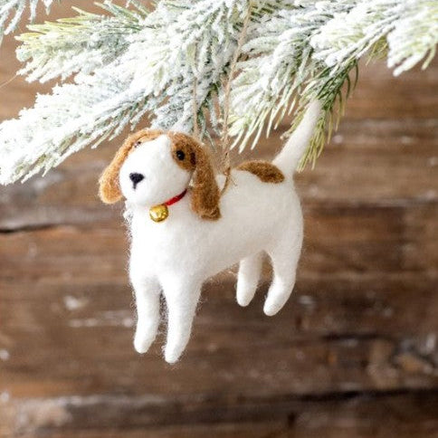 Dog-shaped Christmas ornament hanging on a tree branch with a wooden background