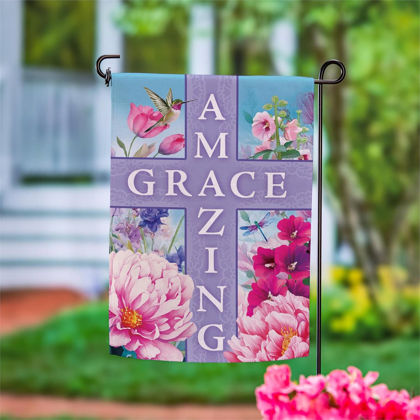 Evergreen Amazing Grace garden flag with a floral design and cross, hanging outdoors.
