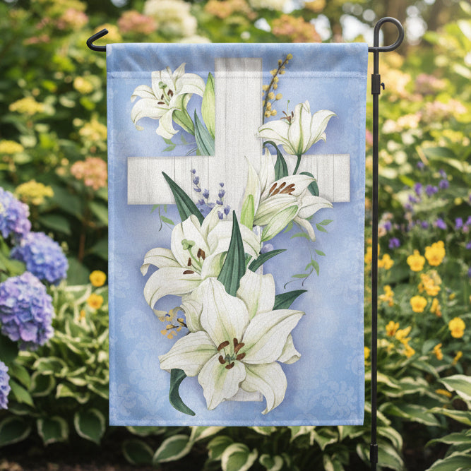 Evergreen Cross of Lilies garden flag with white lilies and a cross on a blue background, hanging outdoors.