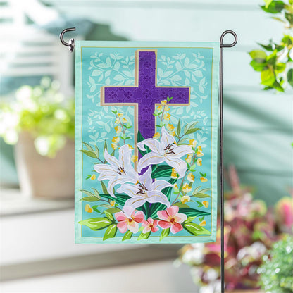 Evergreen Easter Cross garden flag flag with a cross and flowers on a stand outdoors.
