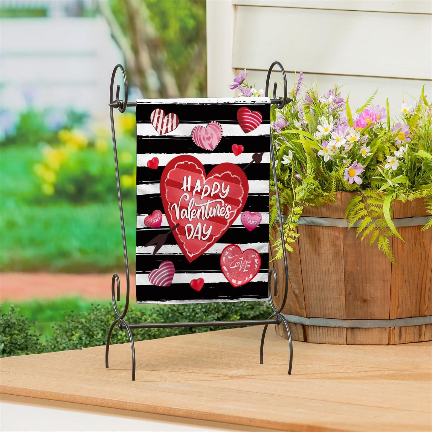 Evergreen Striped Hearts burlap garden flag with hearts on a black and white striped background, placed outdoors.