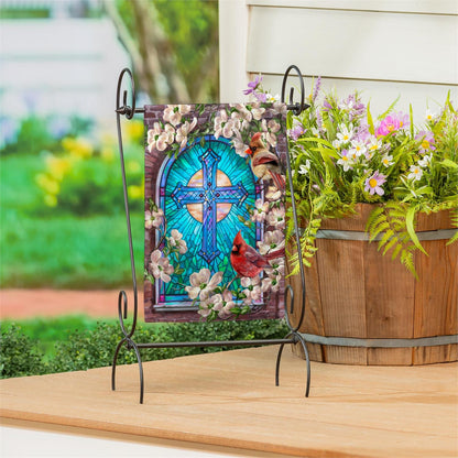Evergreen Sunday Morning garden flag with a stained glass design and cardinals on a stand outdoors.