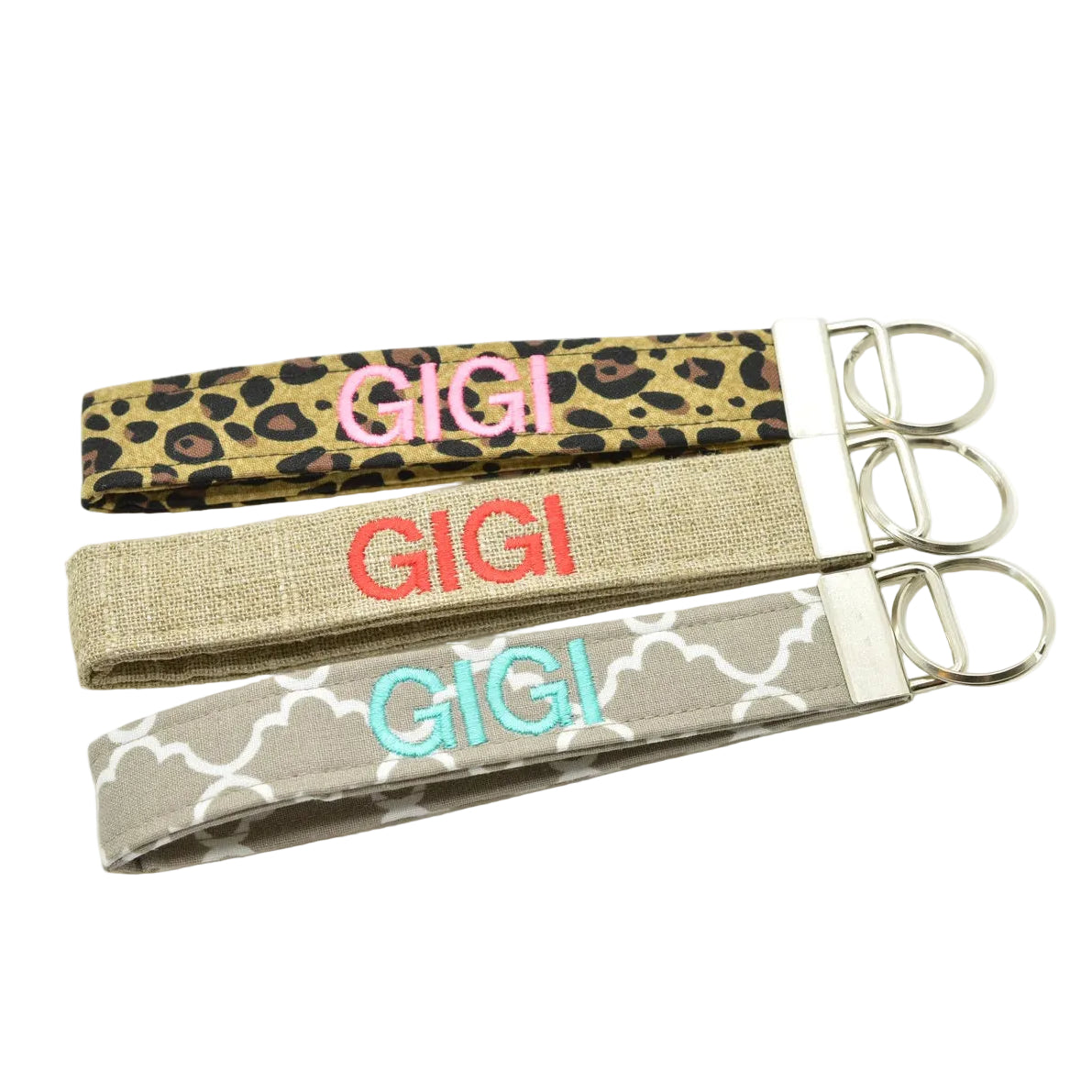 Three fabric keychains embroidered with 'GIGI'. Patterns are leopard, burlap, and grey quatrefoil.
