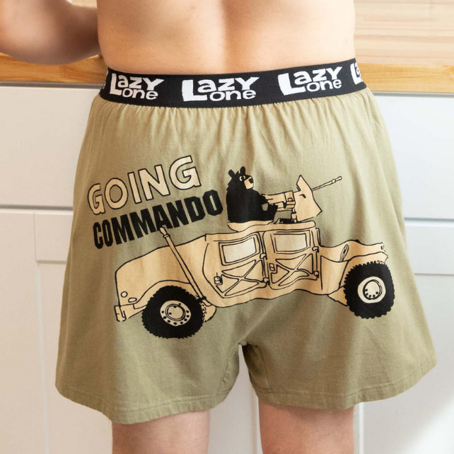 Person wearing a pair of boxer shorts with a graphic design and text, standing in a kitchen.