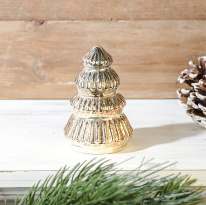 Decorative silver Christmas tree ornament on a wooden surface with pine branches.
