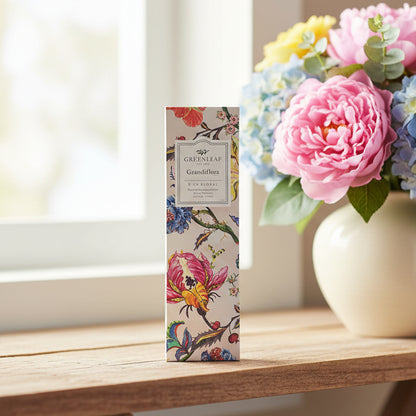 Greenleaf Grandiflora slim sachet on a shelf in front of a window with a vase of flowers next to it.