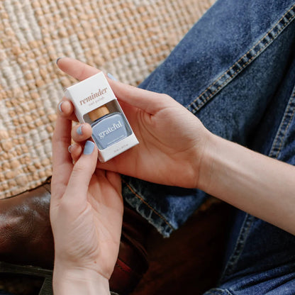 Person holding a small container of Reminder Nail Polish.