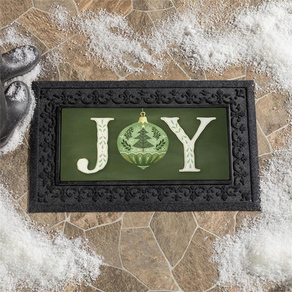Decorative mat with 'JOY' text and Christmas ornament design on a stone surface.