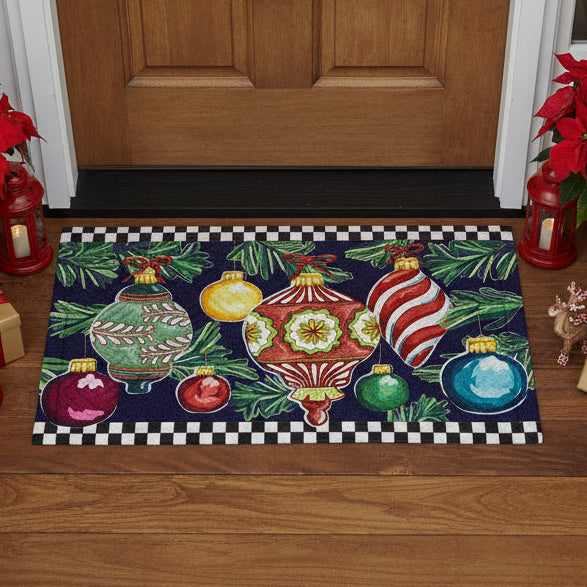 Decorative door mat with colorful Christmas ornaments and greenery on a black background with a checkered border.