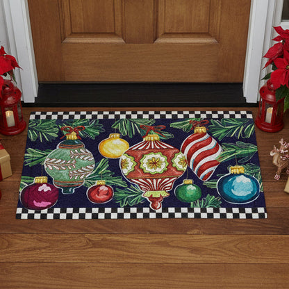 Decorative door mat with colorful Christmas ornaments and greenery on a black background with a checkered border.