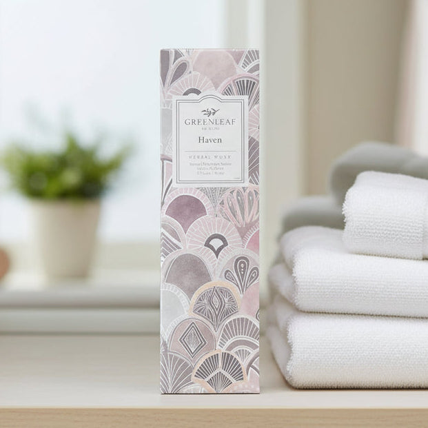 Greenleaf Haven slim sachet on a shelf with white towels next to it and a plant in the background.